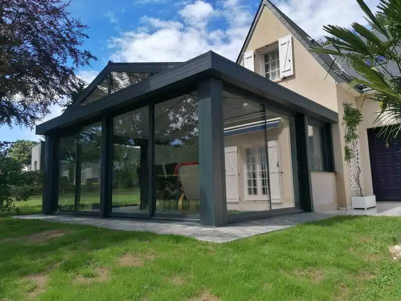 Vue de face oblique de la véranda 'Iris' avec volets roulants à Changé